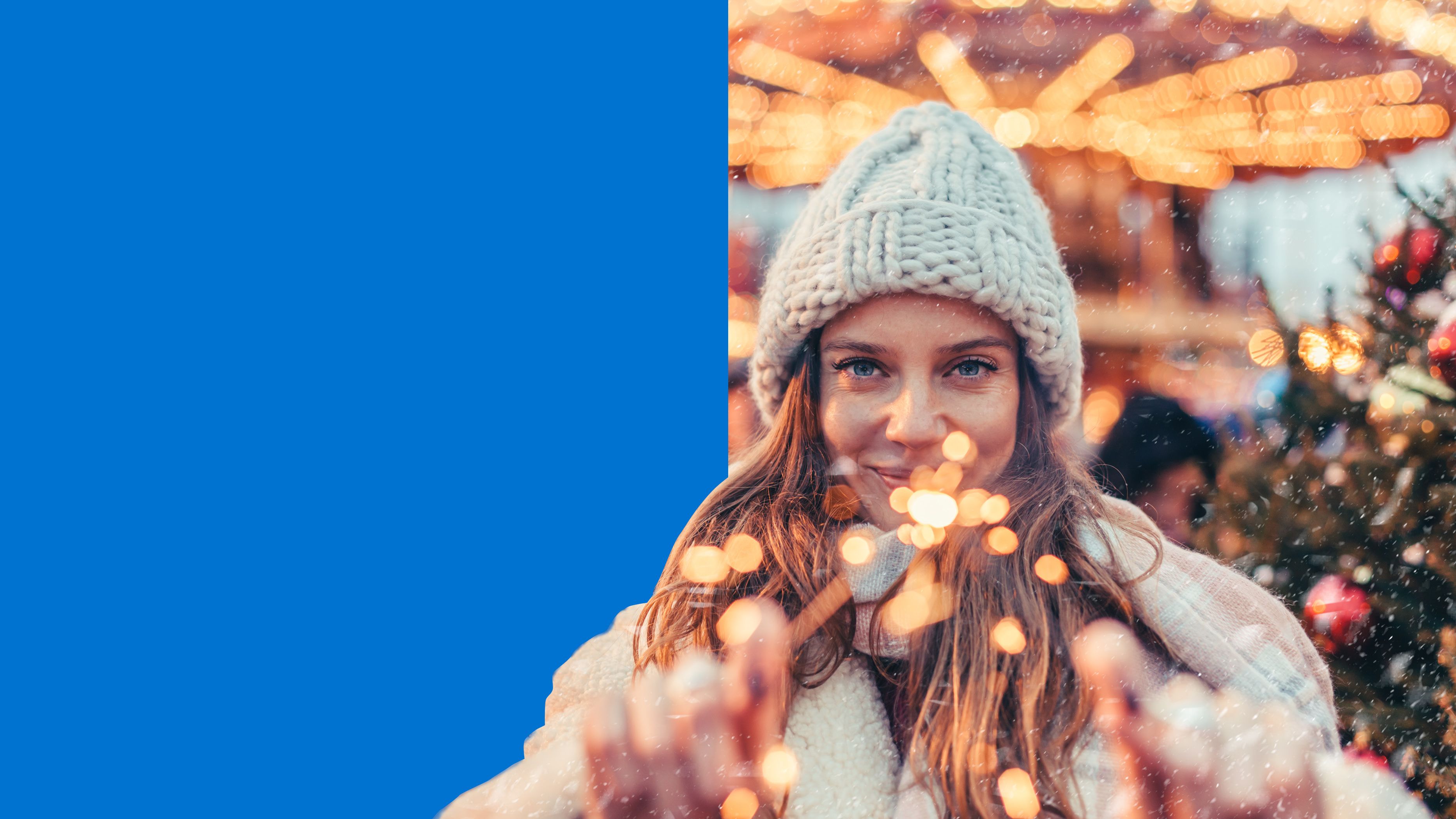 young woman facing camera holding sparklers in front of christmas tree