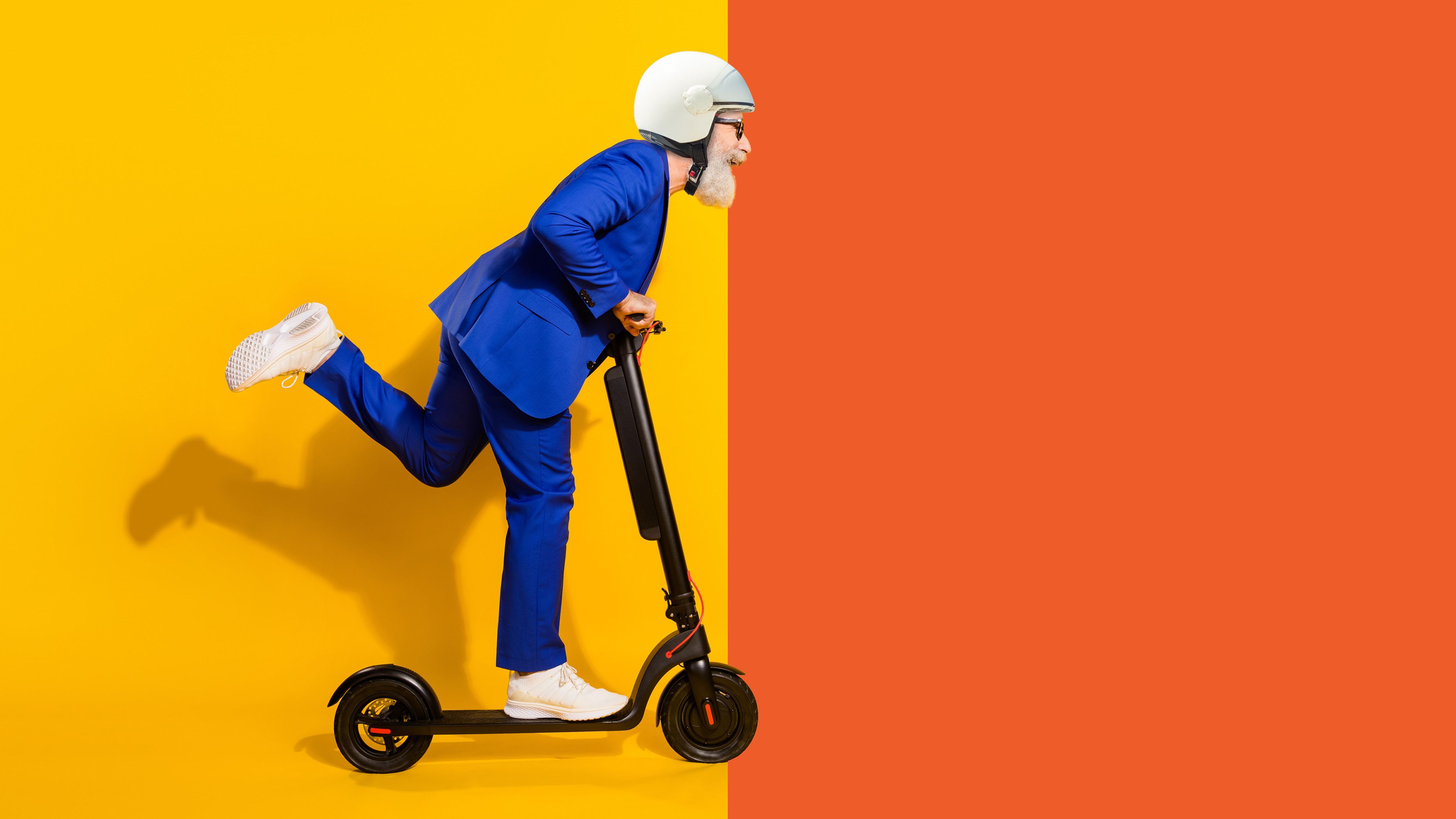 man with white beard and bright blue suit riding a e-scooter 