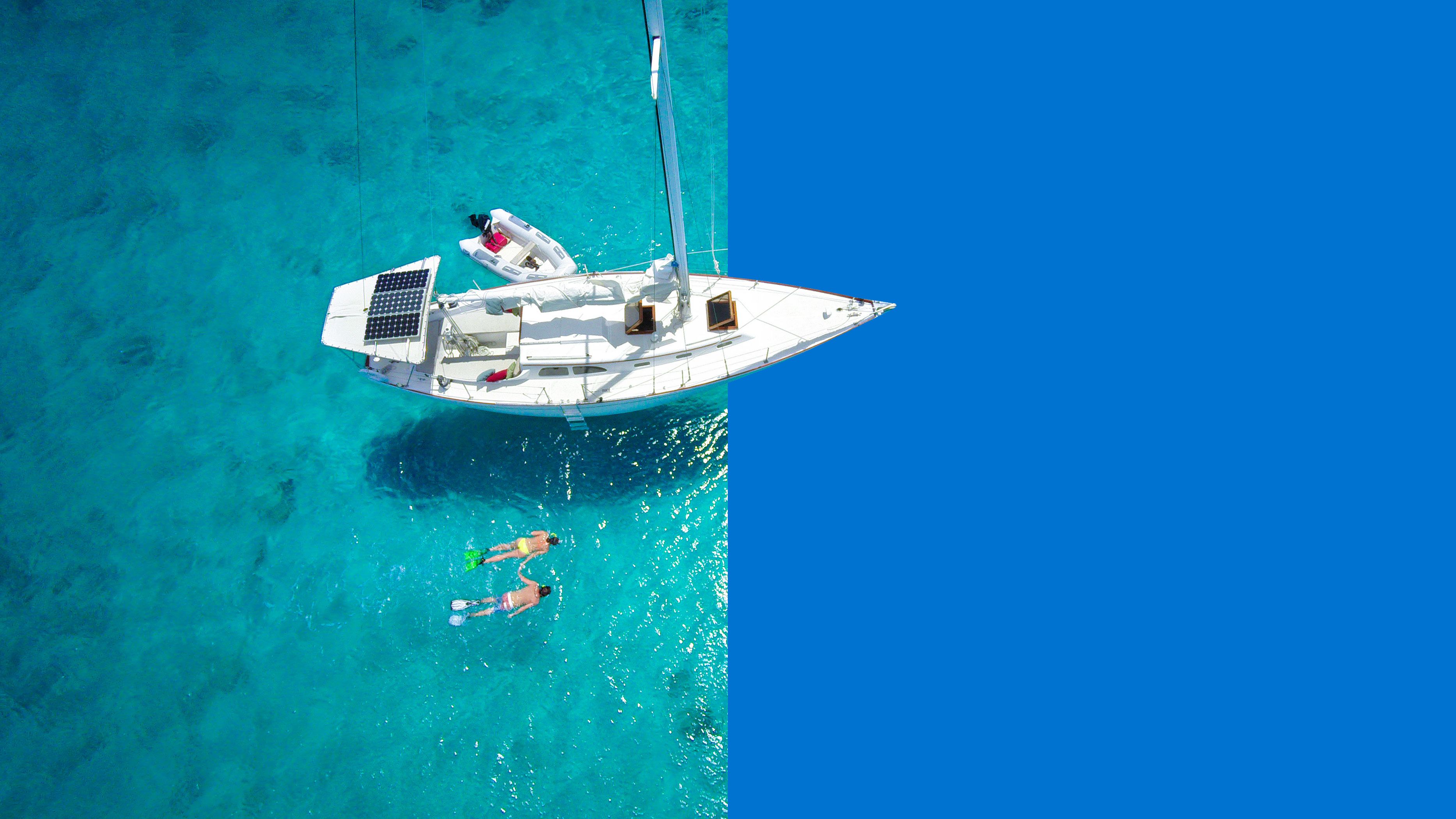 aerial view of couple snorkelling near yacht in tropical water